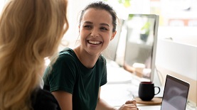 Das Bild zeigt zwei Frauen vor einem Computerbildschirm.